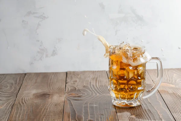 Beer splash in glass on a wooden background — Stock Photo, Image