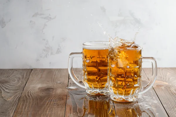 Two Oktoberfest beers splash on a wooden table — Stock Photo, Image