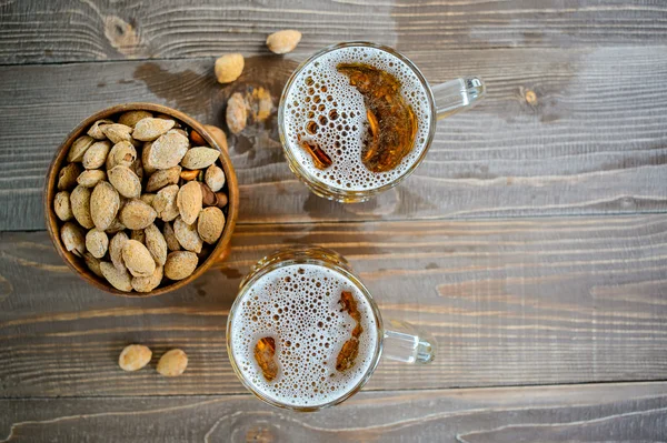 Two Oktoberfest beers with pistachio nuts on a wooden table, top view — Stock Photo, Image
