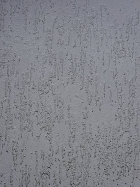 Close-up of the textured surface of decorative facade plaster. Relief, rough structure and play of light and shadow, emphasizes volume. Gray shades. Modern architecture, construction, exterior design