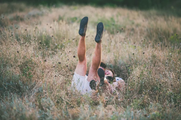 คู่รักหนุ่มนอนบนหญ้า ยืดขาขึ้น — ภาพถ่ายสต็อก