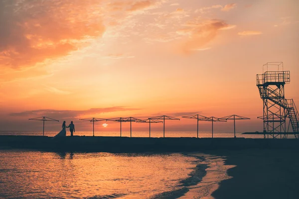 Novia y el novio contra una puesta de sol en el mar —  Fotos de Stock