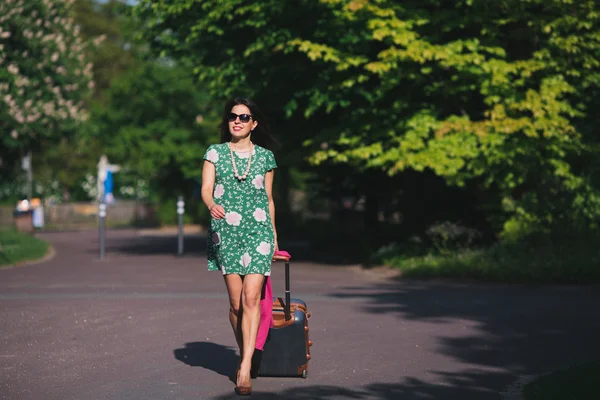 Дівчина йде по дорозі з валізою — стокове фото