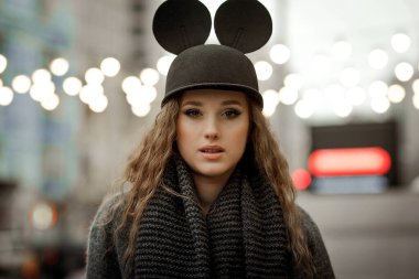 Kulakları olan şık şapkalı bir kız Sonbaharda ya da ilkbaharda şehirde yürür.