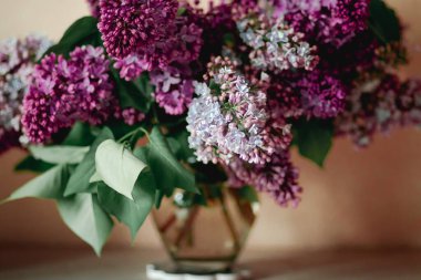 Masanın üstünde bir buket leylak ve su var.