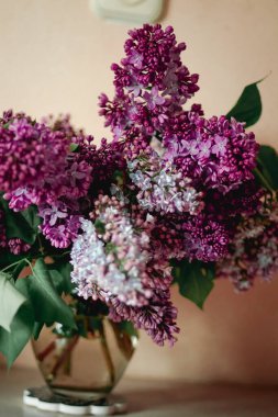 Masanın üstünde bir buket leylak ve su var.