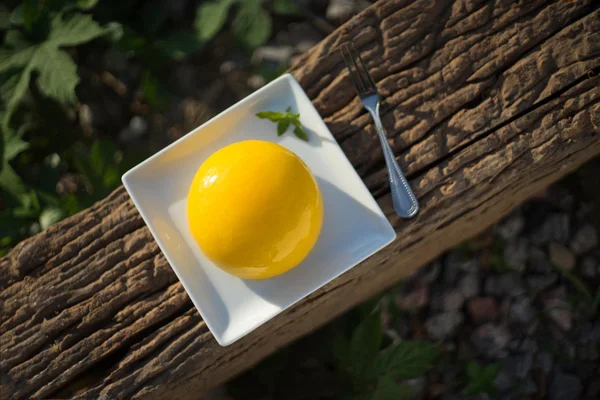 Pastel de esponja con mermelada de naranja en plato blanco y tenedor de plata en pieza de madera y hierba verde en el fondo —  Fotos de Stock