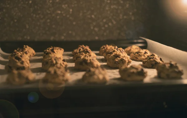 Close-up Schokoladenchips Kekse auf einem Backblech im Ofen, gefiltertes Bild, selektiver Fokus, Fackel hinzugefügt, Lichteffekt hinzugefügt — Stockfoto