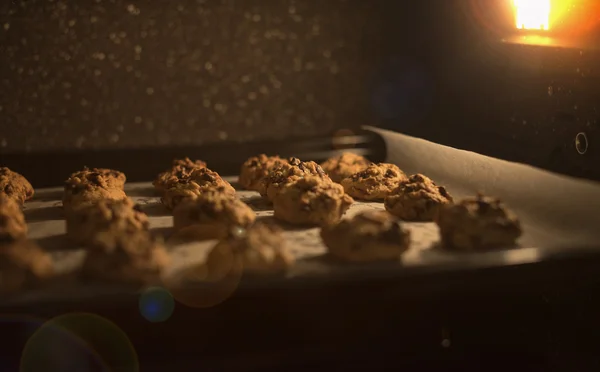 Nahaufnahme Schokoladenkekse auf einem Backblech im Ofen, gefiltertes rotes und braunes Vintage-Image, selektiver Fokus, Fackel hinzugefügt, Lichteffekt hinzugefügt — Stockfoto
