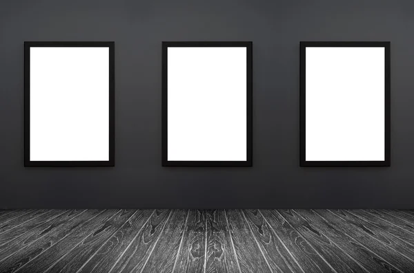 Drei schwarze Rahmen hängen an grauer Wand, weiß isoliert, inkl. Clipping-Pfad in Rahmen, perspektivisch schwarzer Holzboden, für Werbetreibende, Grafiker — Stockfoto