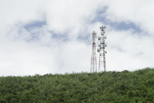 Sloupku telekomunikační stožáru Tv antény bezdrátové technologie na vrcholu zelené hory, modré oblohy a cloud v pozadí, Selektivní ostření — Stock fotografie