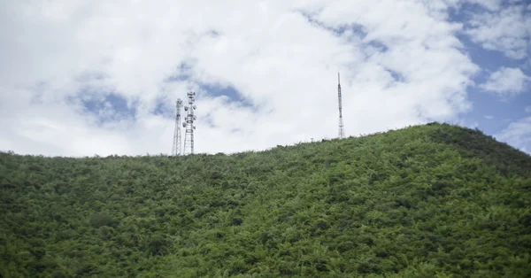 Stolpe av telekommunikation mast Tv antenner trådlös teknik på en kulle av gröna berg, blå himmel och moln i bakgrunden, filtrerade bilden, selektivt fokus — Stockfoto