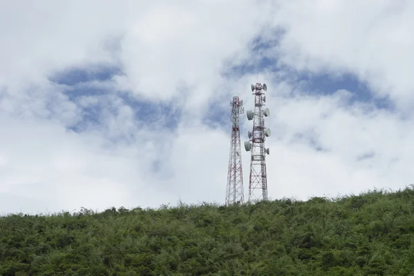 Sloupku telekomunikační stožáru Tv antény bezdrátové technologie na vrcholu zelené hory, modré oblohy a cloud v pozadí, Selektivní ostření — Stock fotografie