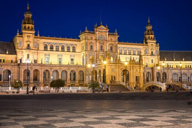 Seville 'deki Plaza de Espana cephesinin akşam manzarası aydınlık çeşme ve kuleyle, lamba direkleriyle, mimari görkem, sıcak ışık ve huzurlu Endülüs atmosferiyle
