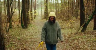 Sarı bereli ve tüylü ceketli genç bir kadının, tasmalı bir köpek ve güzel bir sonbahar ormanında yol alan başka bir köpeğin görüntüsü. Konsept