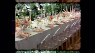 Klasik Super 8 filmi, bir düğün resepsiyonu ya da resmi bir ziyafet için güzel dekore edilmiş uzun bir masa çekti. Tabaklar, kristal bardaklar, pembe peçeteler ve renkli çiçeklerle zarif bir şekilde hazırlanmıştır.