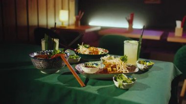 Restoranda bir masa dolusu lezzetli geleneksel Asya yemeği. Akşam yemeğinde Vietnam Pho Bo çorbası, Tayland Pad Thai eriştesi, karides ve tatlı ve ekşi patlıcan var.