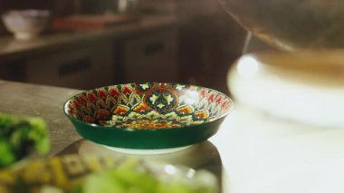 Profesyonel bir şefin Pad Thai eriştelerini siyah eldiven kaplamalı güzel renkli bir seramik kaseye koyarken yakın plan fotoğrafı. Aşçı makarnayı kıvırarak mükemmel bir şekilde hazırlıyor.