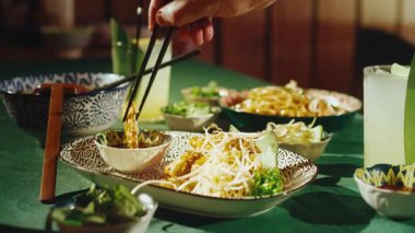 Asya restoranında kızarmış patlıcan yiyen birini yakından çek. Bir erkek el, bir parça sebze tempurasını soya ya ya da acı biber soslu küçük bir kaseye daldırmak için siyah çubuklar kullanıyor.