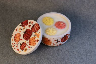 Şenlik kavanozunda balkabağı bulunan bir sonbahar dekoratif mum. Cadılar Bayramı ve sonbahar tatilleri için konfor, mevsimlik dekor ve temalı süslemeler..
