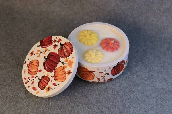 Şenlik kavanozunda balkabağı bulunan bir sonbahar dekoratif mum. Cadılar Bayramı ve sonbahar tatilleri için konfor, mevsimlik dekor ve temalı süslemeler..