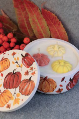 Handmade autumn decorative candle in a plaster jar with painted pumpkins  cozy autumn decor, home fragrance, and festive atmosphere