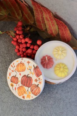 Handmade autumn decorative candle in a plaster jar with painted pumpkins  cozy autumn decor, home fragrance, and festive atmosphere