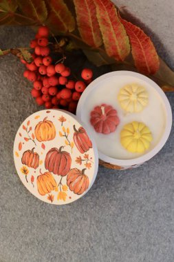 Handmade autumn decorative candle in a plaster jar with painted pumpkins  cozy autumn decor, home fragrance, and festive atmosphere