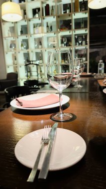 Şarap kadehiyle, pembe peçeteyle ve dekoratif ışıklandırmayla bir restoranda şık masa ayarı: gastronomi, restoran servisi, iç tasarım, şenlikli etkinlikler, görgü kuralları, bloglar, sosyal medya, sunumlar hakkında içerik fotoğrafı