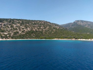 A deep blue bay with a sandy coastline and green hills under a clear sky in Bodrum