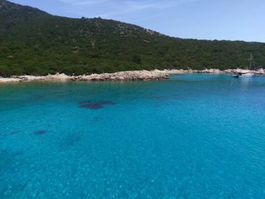 Bodrum 'un bozulmamış kıyı şeridi derin mavi denizi, kumlu plajları ve açık gökyüzünün altındaki yeşil tepeleriyle