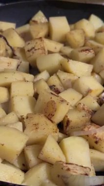 Altın kabuklu, baharatlı ve karamelli soğanlı kızarmış patates küplerinin yakın çekimi.