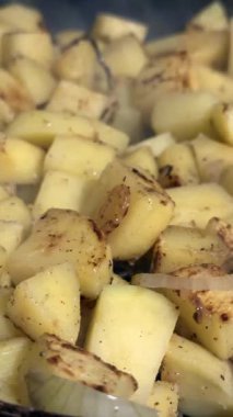 Altın kabuklu, baharatlı ve karamelli soğanlı kızarmış patates küplerinin yakın çekimi.