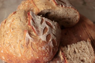 Dekoratif kesimli zanaatkar ekmeği ve ahşap bir yüzey üzerindeki gözenekli ekmek kırıntısı fırın markası için idealdir.