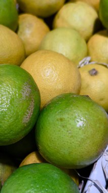 Turunçgillerin markalaşması için ideal bir pazar ortamındaki doğal deri dokusuna sahip taze yeşil ve sarı limonlar yakın plan.