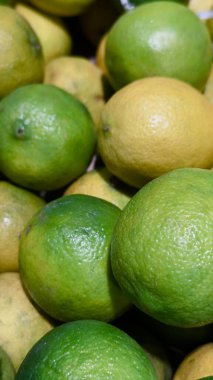 Turunçgillerin markalaşması için ideal bir pazar ortamındaki doğal deri dokusuna sahip taze yeşil ve sarı limonlar yakın plan.