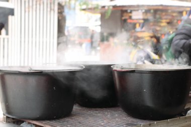Yemek için metal bir ızgaranın üzerinde kaynayan siyah kazanlar olan sokak yemekleri sahnesi