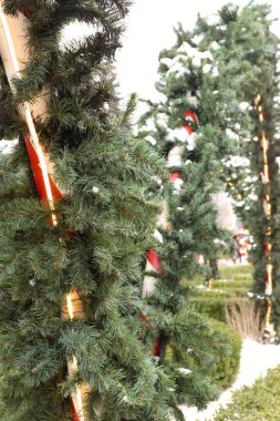 Çelenkli çizgili sütunlar ve şenlikli bir açık hava tesisinde yapay kar.