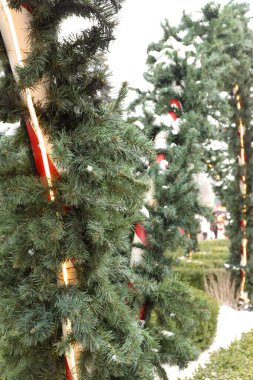 Çelenkli çizgili sütunlar ve şenlikli bir açık hava tesisinde yapay kar.