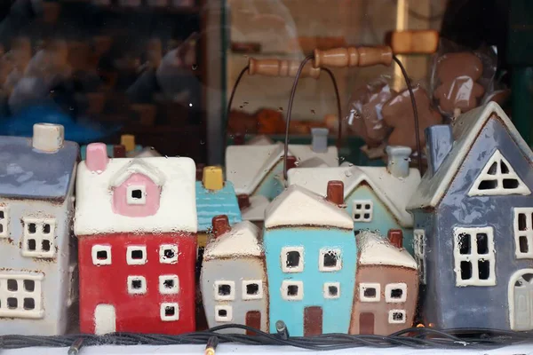 Minyatür seramik evlerin olduğu küçük sandık, rahat bir iç mekanda, yağmur camı arkasında.