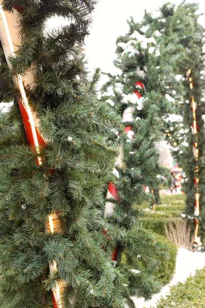 Çelenkli çizgili sütunlar ve şenlikli bir açık hava tesisinde yapay kar.