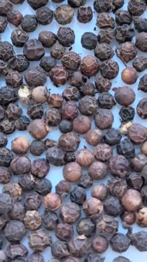 Siyah karabiberlerden oluşan dönüşümlü bir yakın plan, organik yemek pişirme, sağlıklı beslenme ve mutfak tasarımı kavramları için baharatlı bir zemin..