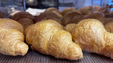 Bir pastane vitrininde kruvasanların yakın plan çekimi, altın kruvasanları reklam ve tasarım için iştah açıcı olarak kullanmak.