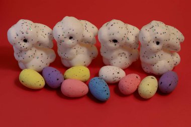 Puantiyeli tavşanlar ve Paskalya usulü benekli yumurtalar şenlikli bahar dekorasyonu için kırmızı arka planda.