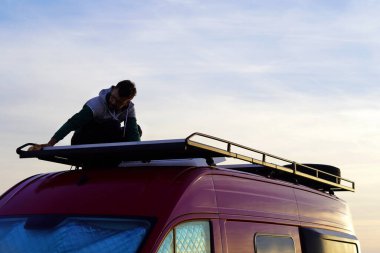 Araçların kamuflajlanması. Adam karavanına güneş panelleri kuruyor..