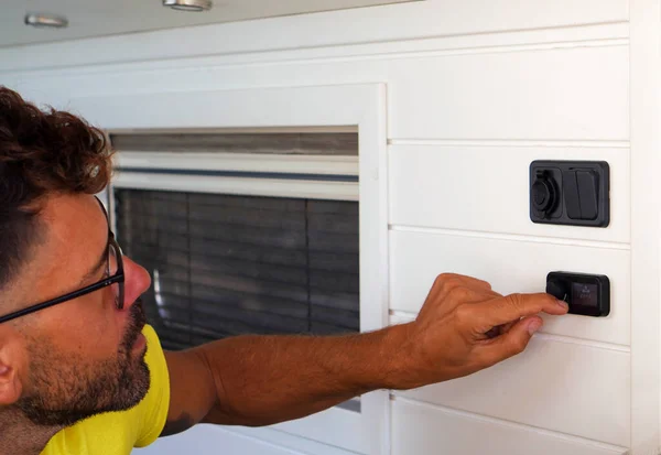 Adam karavanının içindeki iklim kontrol sisteminin sıcaklığını ayarlıyor.