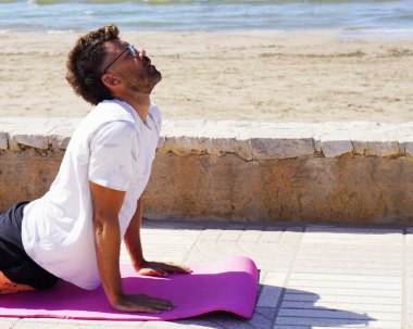 Akıl sağlığım yerinde. Orta yaşlı bir adam plajda yoga yapıyor, gözleri kapalı ve kobra pozu veriyor..