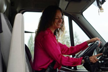 Orta yaşlı kadın ve küçük işletmeler. Pembe tişörtlü serbest çalışan bir kadın minibüsünü sürüyor ve adresi GPS 'e giriyor..