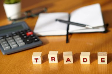 TRADE. Finansal ve iş kavramları. Arkaplanda hesap makinesi ve defter olan tahta bloklardaki harfler