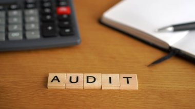 AUDIT. İş ve finansal kavramlar. Hesap makinesi ve not defteri olan tahta harfler..